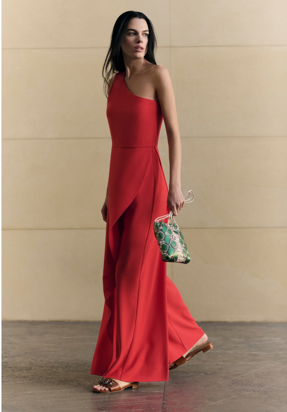 Mujer caminando, con sandalias cafes, vestido rojo y bolso de mano color verde