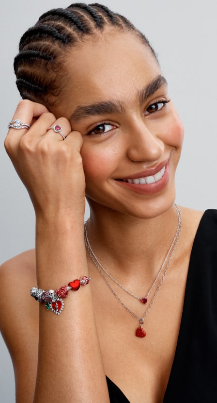 mujer con anillos. collar y pulcera, plateados con rojo  PANDORA