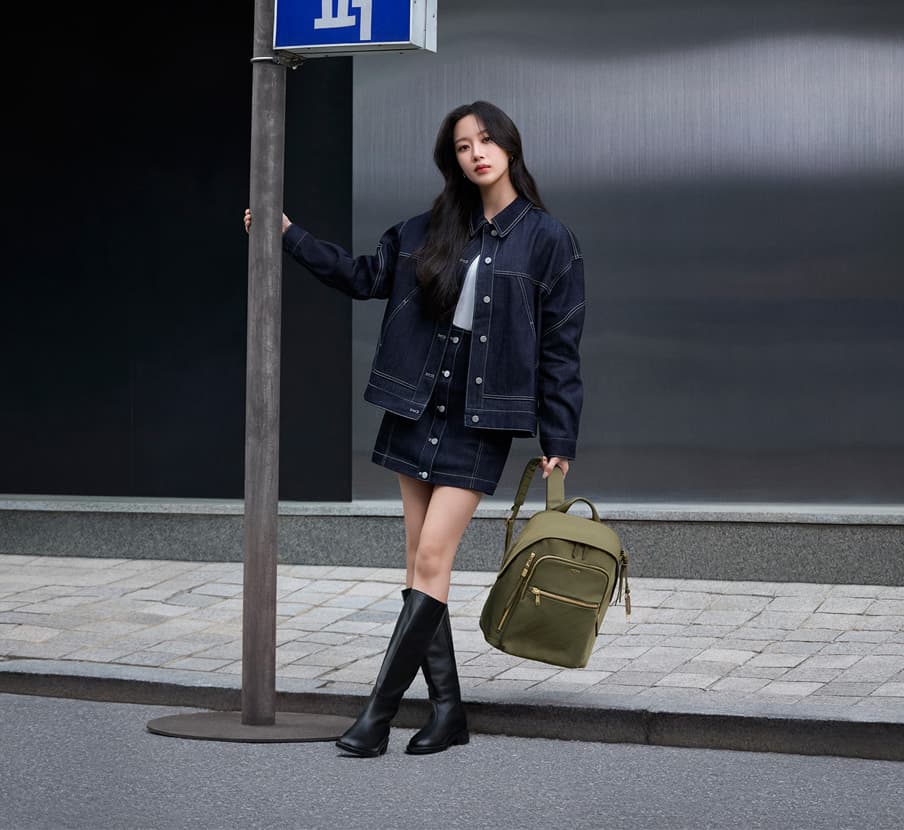 imagen de mujer con ropa azul de mezclilla y mochila verde TUMI