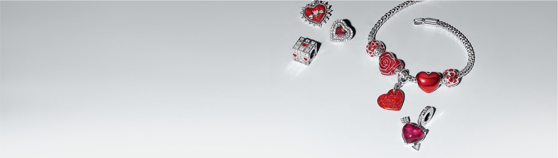 Imagen pulcera plateada con charms rojos. PANDORA