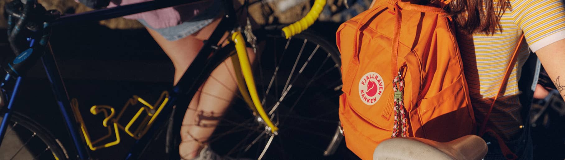 imagen de mujeres en bicicleta y con mochilas amarillas  FJALLRAVEN