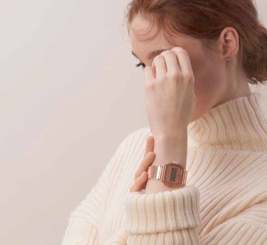 Imagen de una mujer en la mano izquierda se ve un reloj dorado, de la marca CASIO