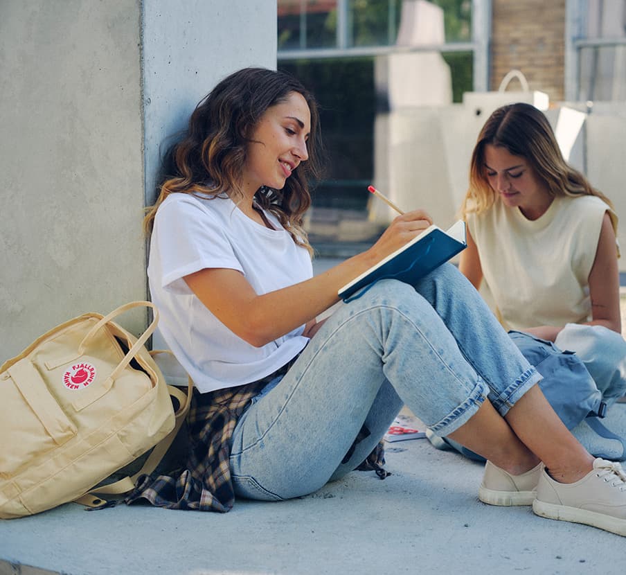 imagen de mujer escribiendo en un cuaderno azul, fjallraven