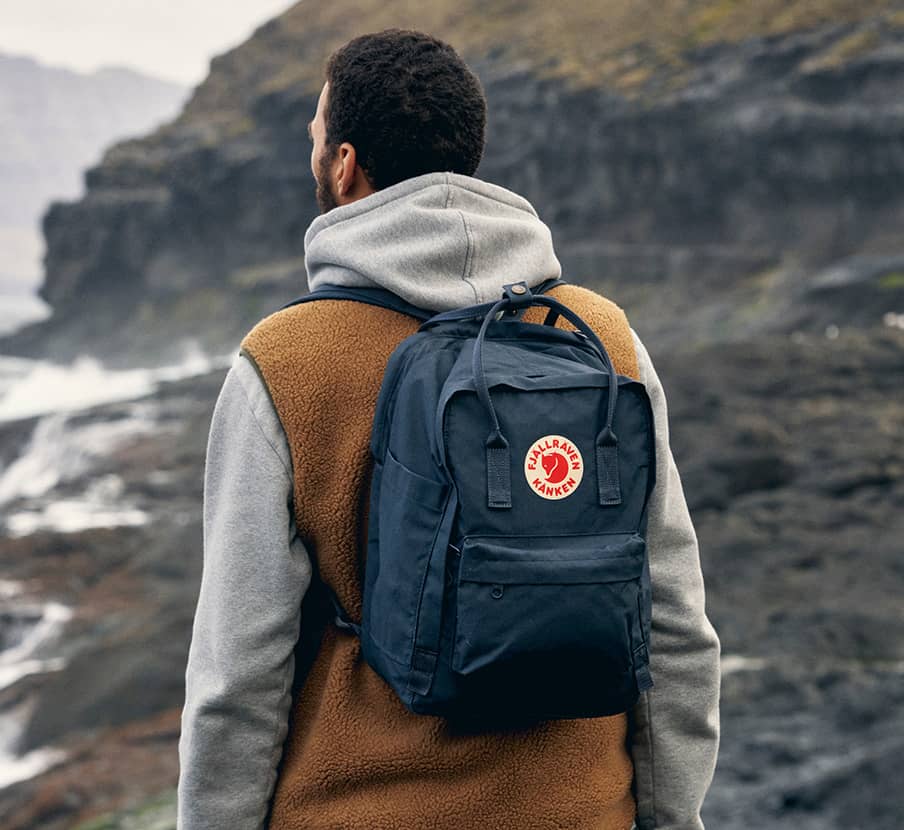 imagen de mhombre con chamarra cafe y mochila azul marino, fjallraven