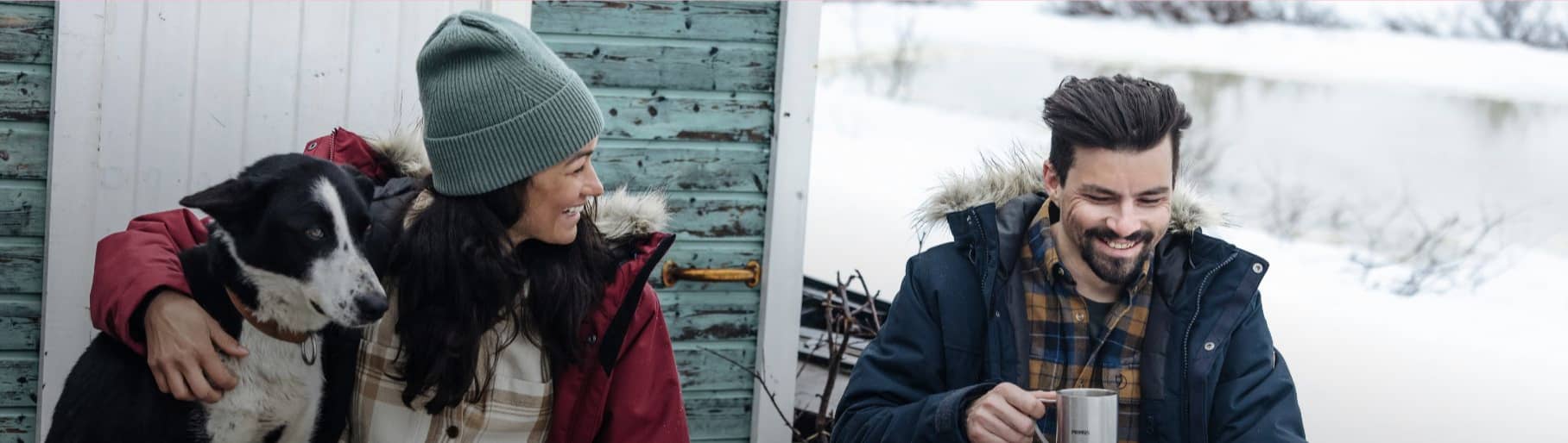 imagen de mujeres, con chamarra roja y gorro gris abrazando un perro, y un hombre tomando cafe con chamarra azul  FJALLRAVEN